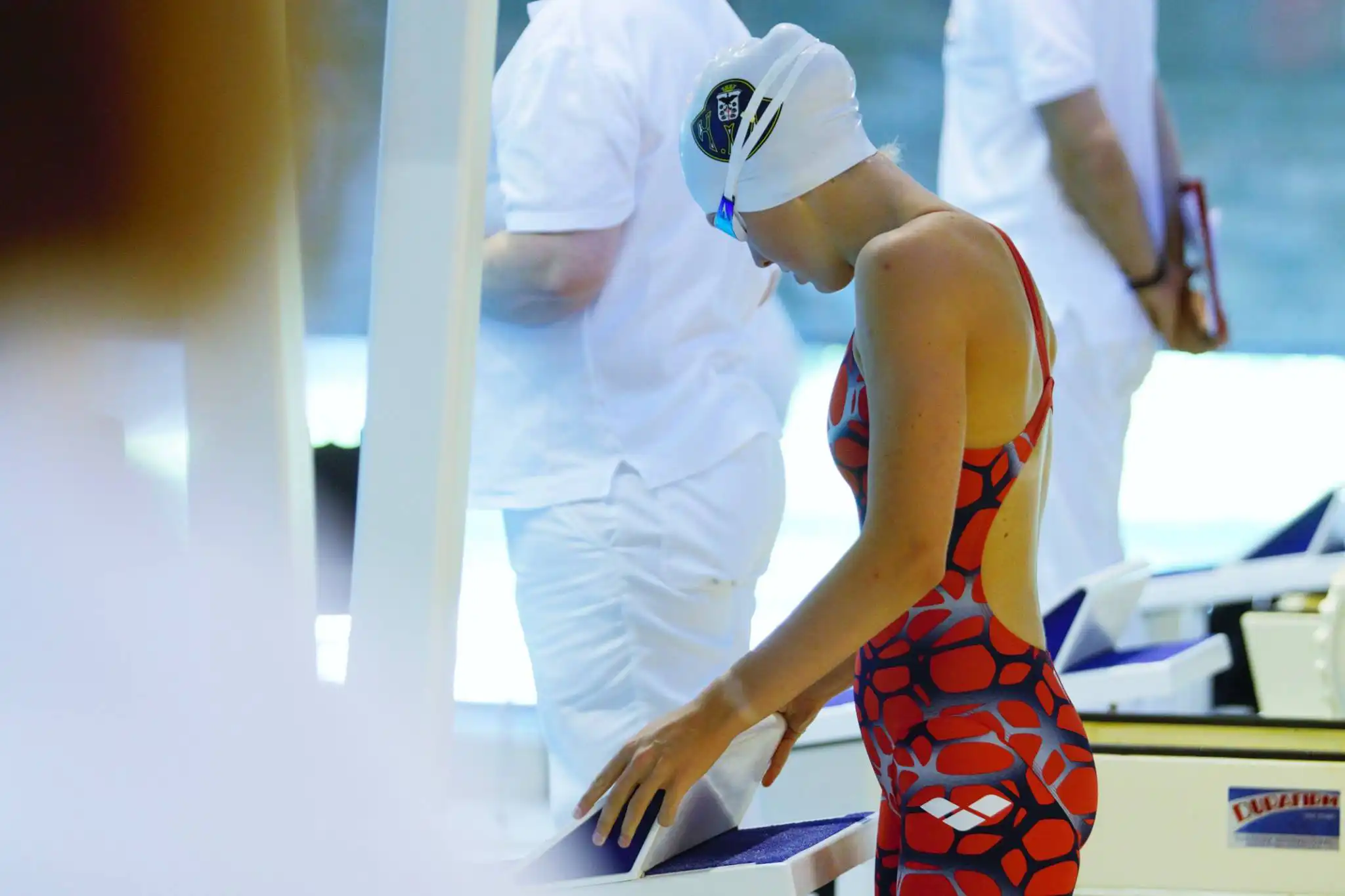 Jente som gjør seg klar til konkurransesvømming, hun står bak en startpall
