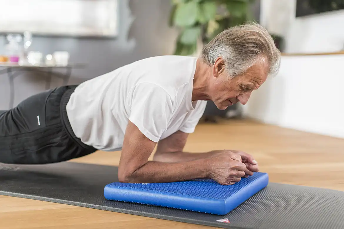 Eldre herremann som trener på en Airex Solid Balansepute