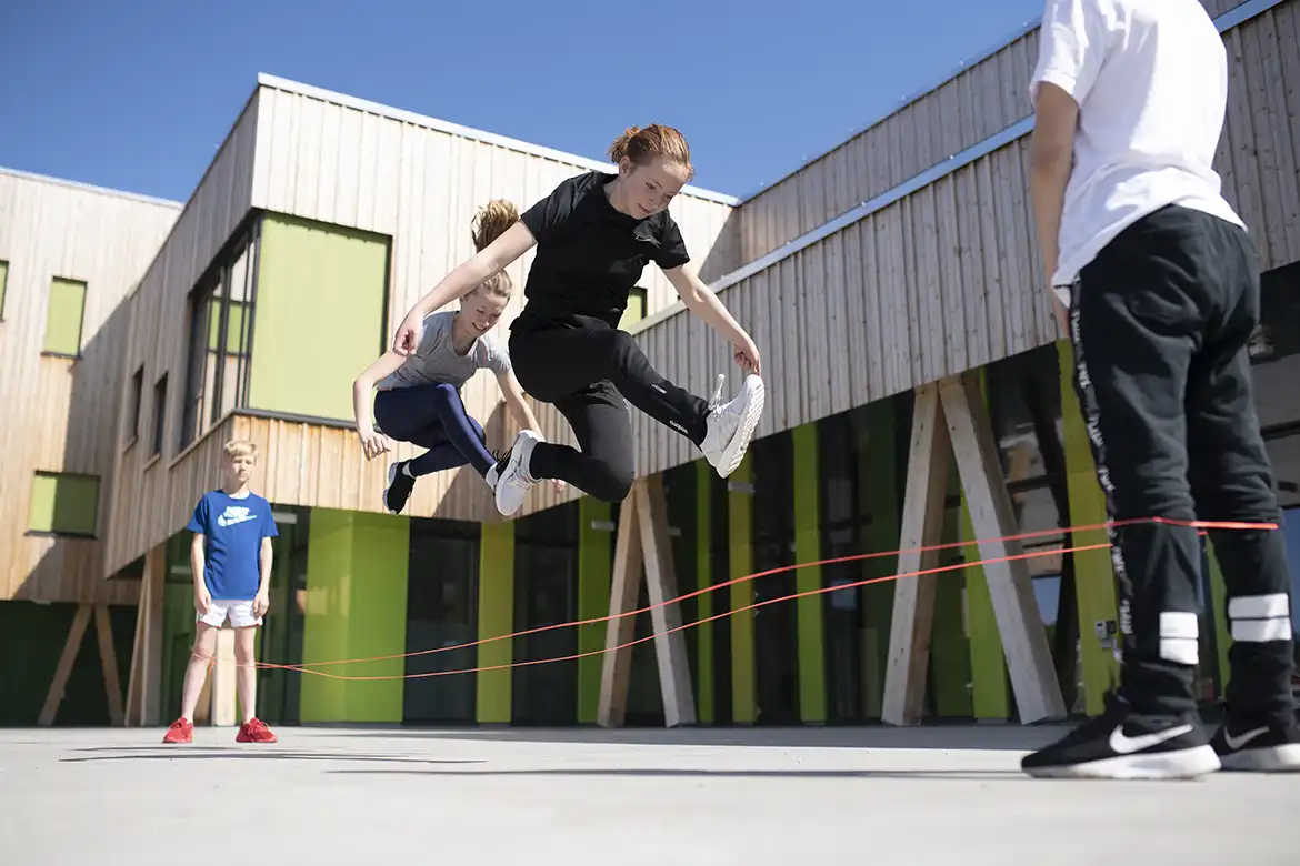 To jenter som hopper strikk ute i skolegården