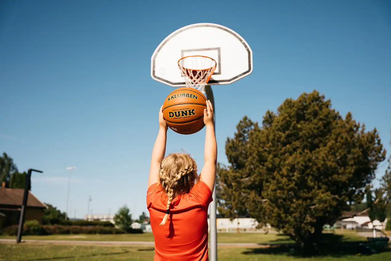 Jente som spiller basketball utendørs