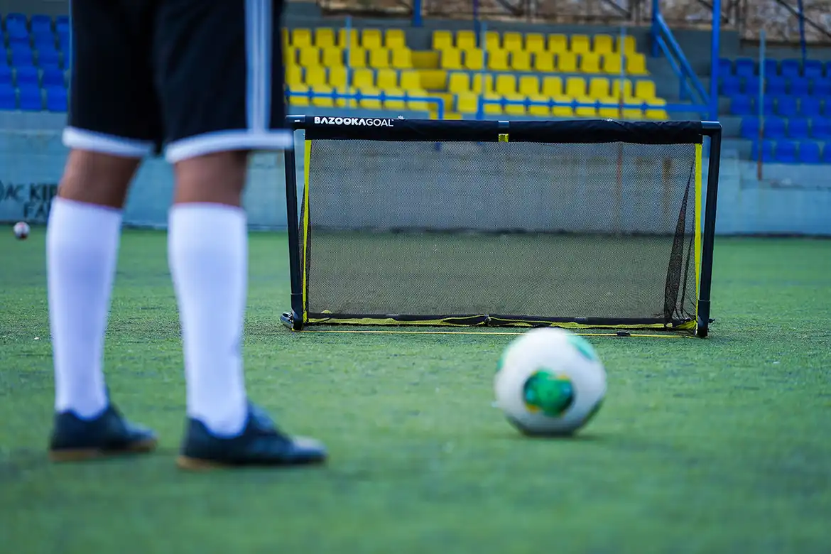 En fotballspiller som skyter en fotball mot et BazookaGoal 