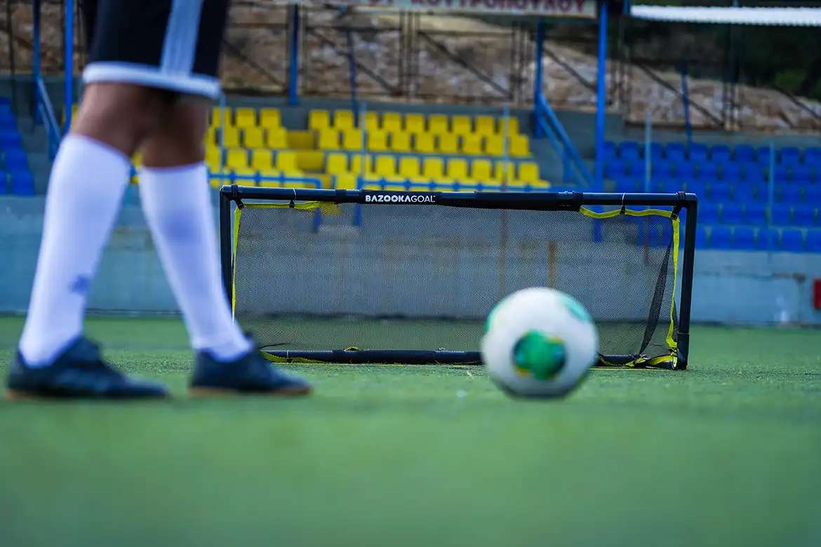 En fotballspiller som skyter en fotball mot et BazookaGoal med justerbar tverrligger