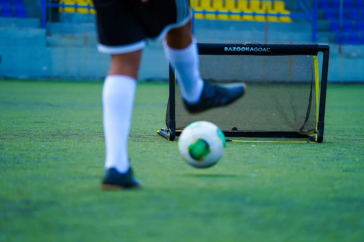 En fotballspiller som skyter fotballen mot et BazookaGoal - original
