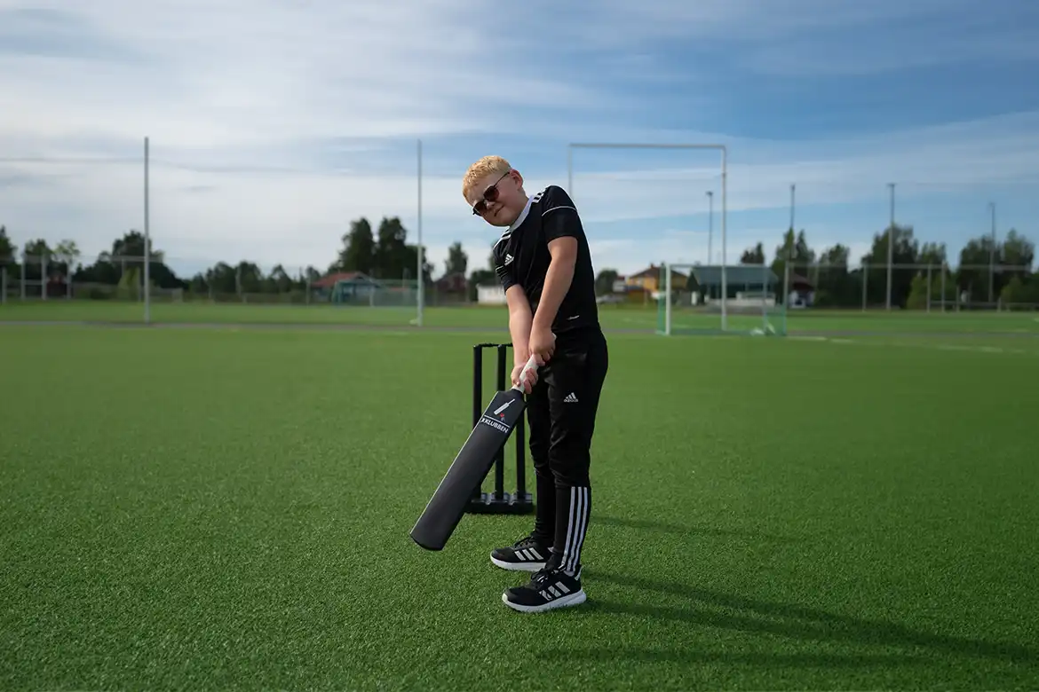 Elev øver på slag med cricketbat og wicket på en utendørs idrettsbane