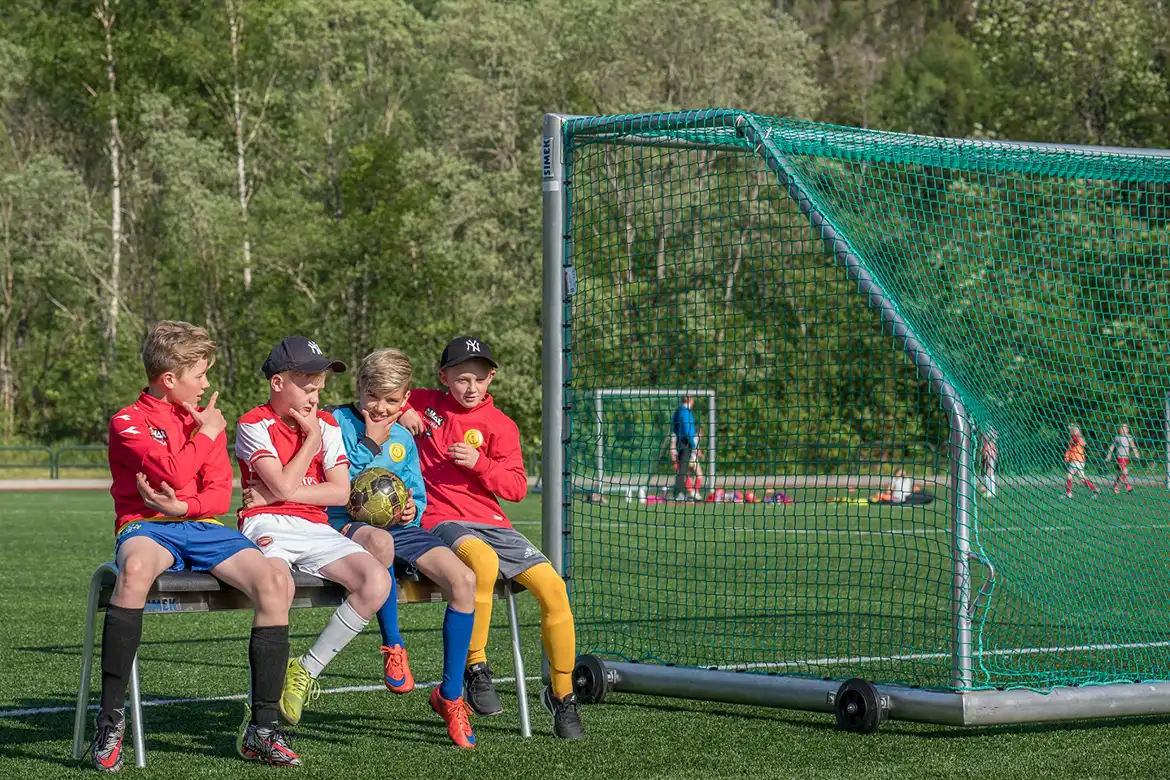 Fire gutter sitter ved siden av et fotballmål etter å ha trent fotball