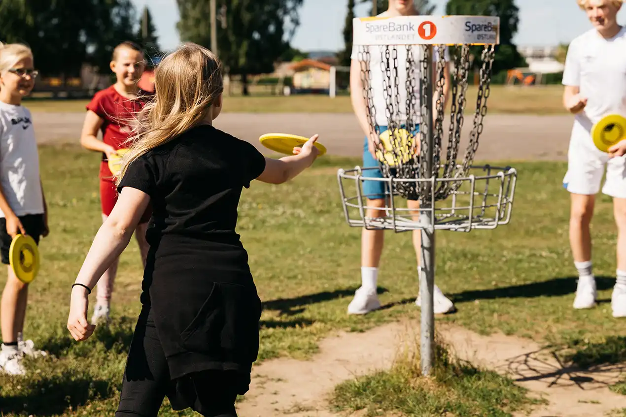 Glade barn som spiller frisbeegolf utendørs