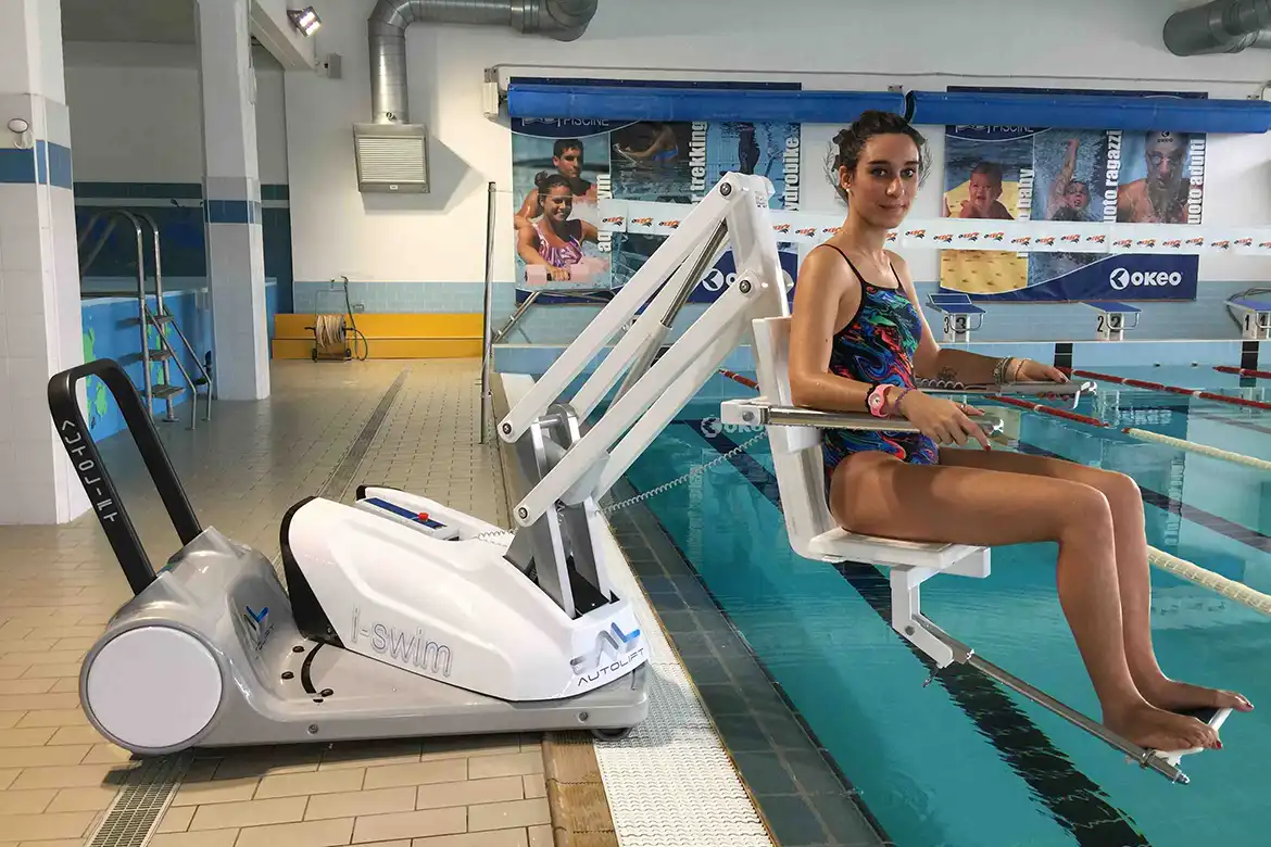 En ung dame sitter i en bassengheis på vei ned i svømmebassenget