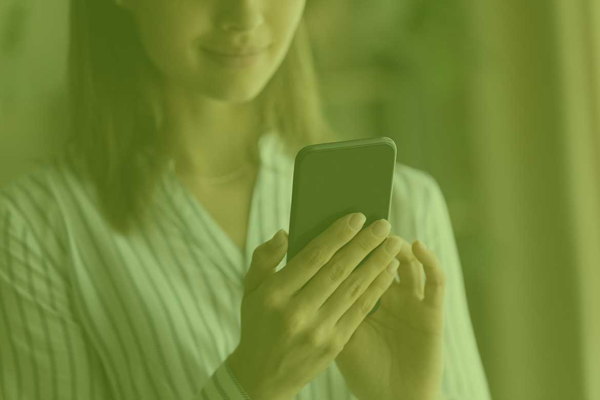 En dame som holder i en mobiltelefon for å skrive melding
