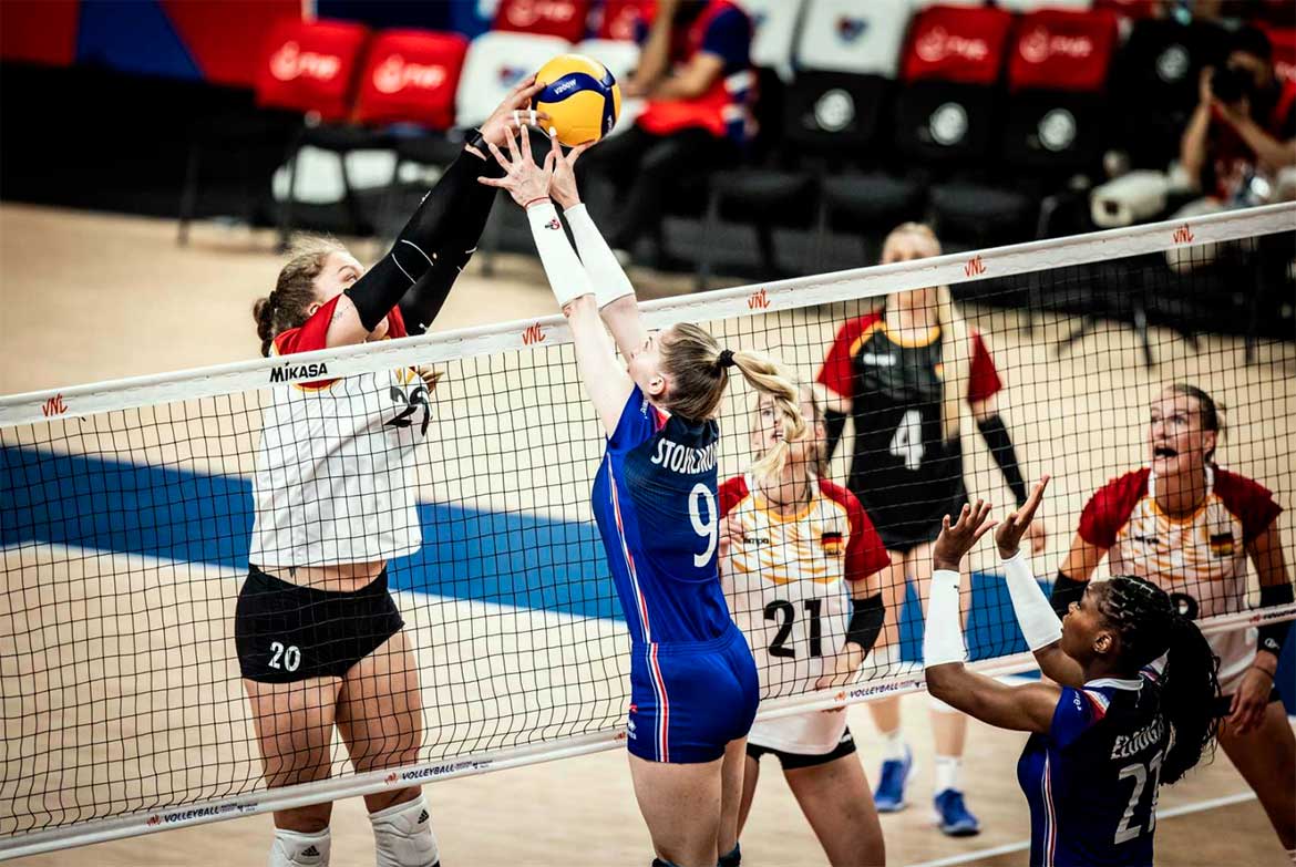 Damer som spiller volleyball innendørs med Mikasa volleyball