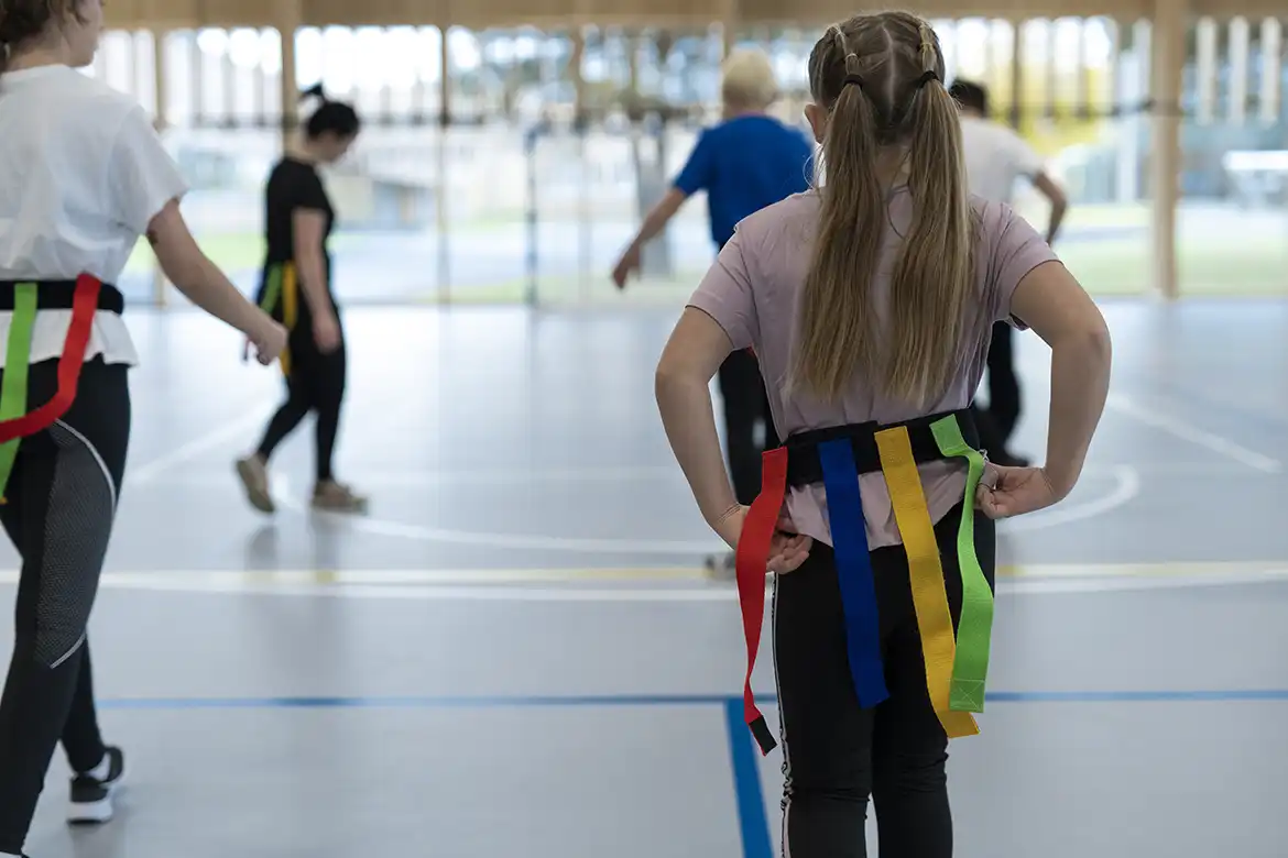 En skoleklasse leker nappehalelek i gymsalen