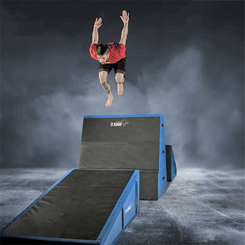 Utøver utfører et hopp over blå og svarte O'Jump parkourmoduler i ulike høyder.