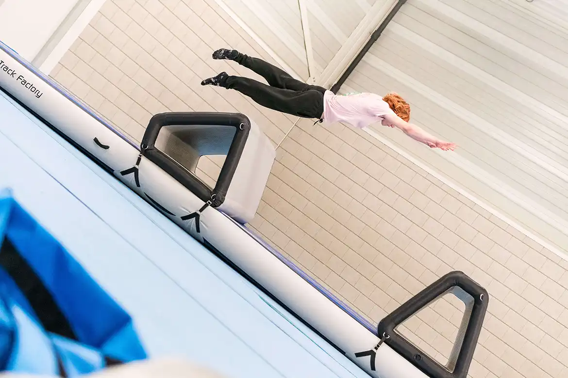 Parkourutøver i svevet over et hinder på en AirTrack