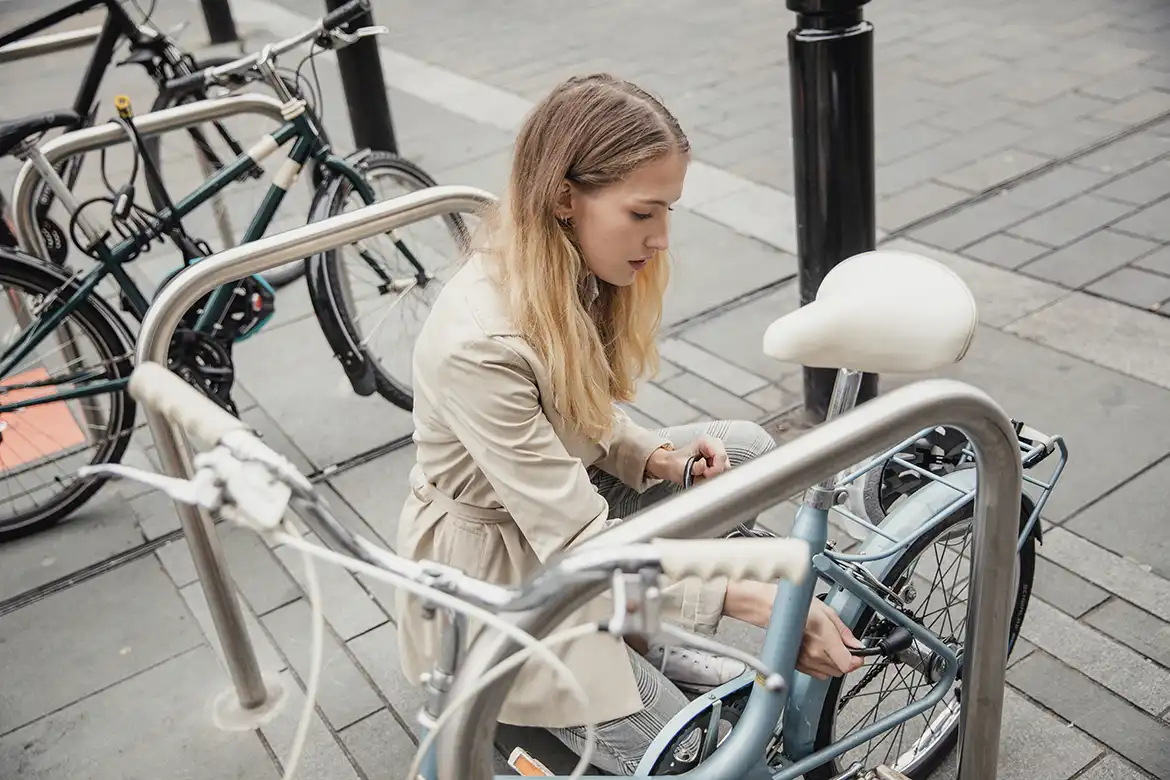 Ung dame parkerer sin sykkel i et sykkelstativ