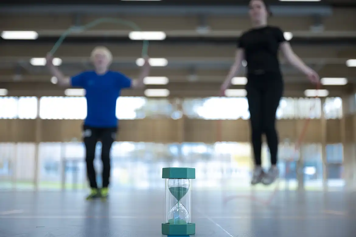 Barn som hopper tau på tid - tiden måles av et timeglass