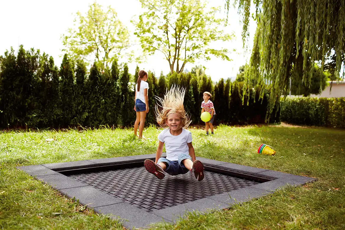 Glade barn som hopper på trampoline utendørs