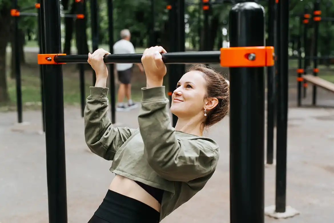 Ung dame trener pull-ups i en utendørs treningspark